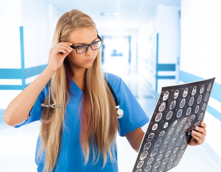 Female doctor looking at tomogram in hospital's corridorの写真素材