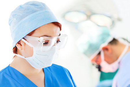 Young female doctor in operation room with surgeon on background