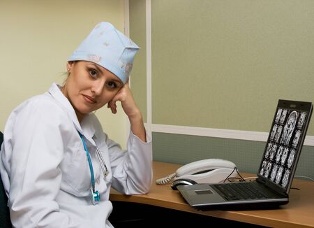 Young female doctor on a desk with a notebook and phone in the officeの写真素材