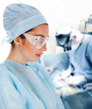 Young Female Surgeon with Medical Team in Back on Surgeryの写真素材