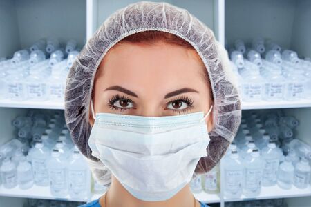 Young Female Doctor with Infusion Bottles in a Cupboard on Backgroundの写真素材
