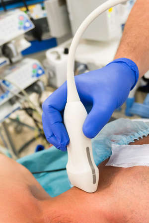 Doctor performs ultrasound examination of the neck vessels in the operating roomの写真素材