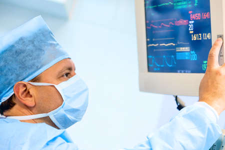 Doctor cheking patient's vital sign at monitor in operating room. Vital sign monitor during surgery in operation room.の写真素材