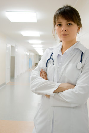 Young female doctor in clinic's corridor under lampsの写真素材
