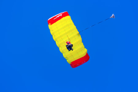 Man gliding down on a parachute in blue skyの写真素材
