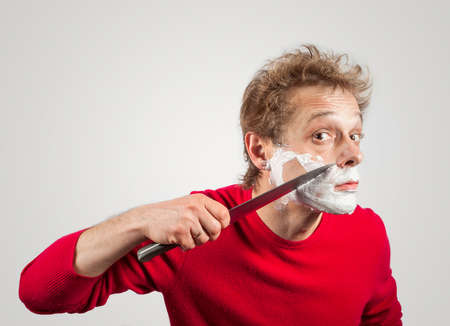 Man shaving with a large kitchen knifeの写真素材