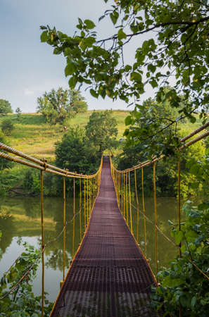 Metal suspension bridge over the riverの写真素材