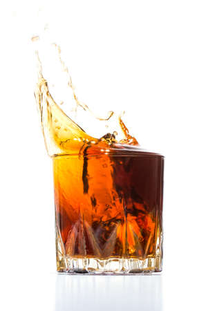 Glass with whiskey splash on white backgroundの写真素材
