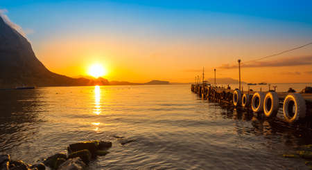 Beautiful golden sunset above the sea and mountainの写真素材