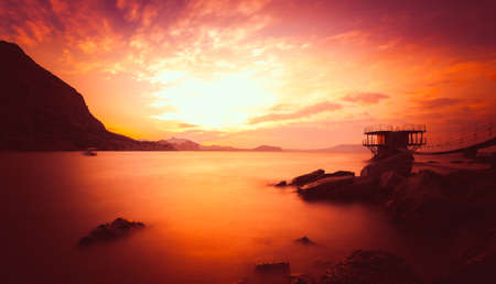 Beautiful golden sunset above the sea and mountainの写真素材