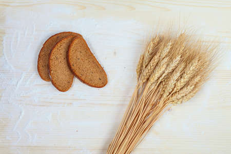 Rustic bread and wheat on an old planked wood tableの写真素材