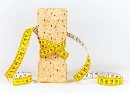 A yellow measuring tape wrapping wheat cracker or crispbread - healthy eating conceptの写真素材