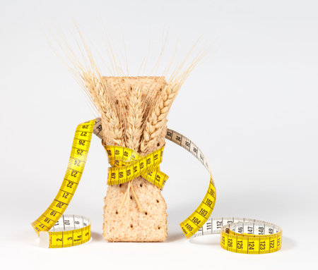 A yellow measuring tape wrapping wheat cracker or crispbread - healthy eating conceptの写真素材