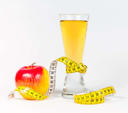 A yellow measuring tape wrapping red apple and juice - healthy eating conceptの写真素材