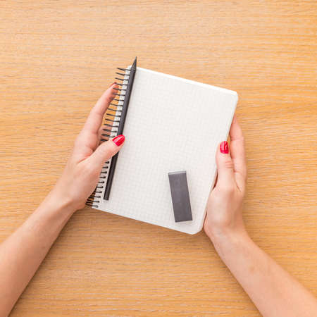 Woman hand holding notebook on wooden backgroundの写真素材