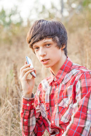 Young smiling student talking on mobile phone in a city parkの写真素材
