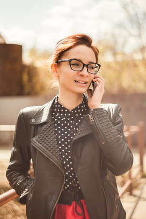 Beautiful girl talking on telephone in townの写真素材