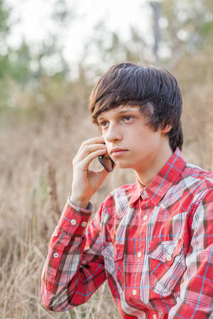 Young student talking on mobile phone in a city parkの写真素材