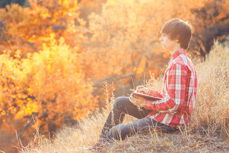 Young student working in autumn city parkの写真素材