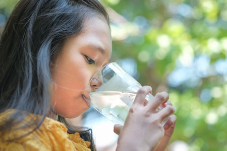 The girl is drinking cold water from the glass.の写真素材