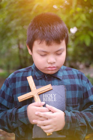 Christian boy  prayer to God. The Bible and the cross are in hand.の写真素材