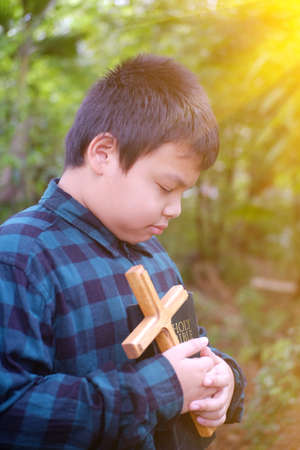 Christian boy  prayer to God. The Bible and the cross are in hand.の写真素材