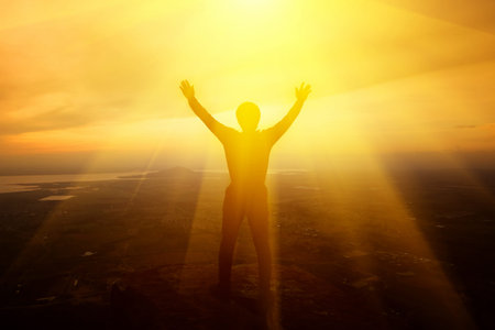Man raising his arms to thank God on the mountain