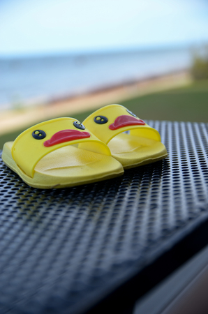 Yellow sandals duckling for kid on table beside the beach and swimming poolの写真素材