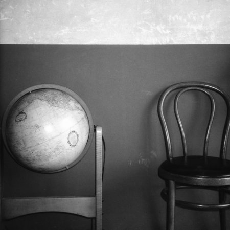 Antique black and white replica globe beside the vintage wooden chair in an old Thai shop.の写真素材