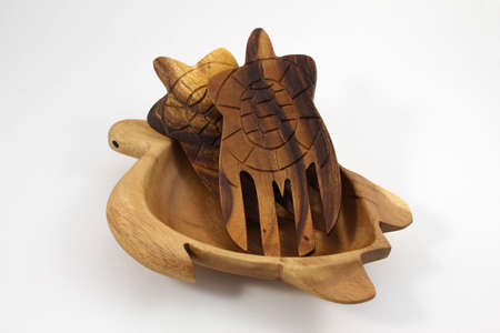 Hand-carved wooden turtle bowl with oriental wooden salad serving hands on white backgroundの写真素材
