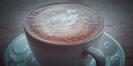 Latte art coffee on the wooden table. (vintage tone)の写真素材