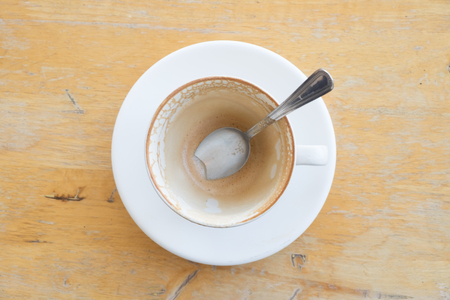 An empty cup of latte coffee with coffee stain on a wooden table.の写真素材