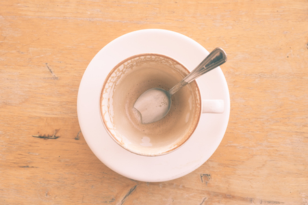 An empty cup of latte coffee with coffee stain on a wooden table. (vintage tone)の写真素材