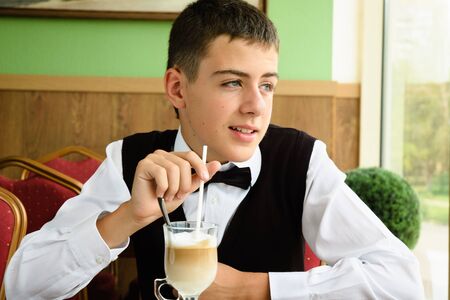 a teenager boy enjoying coffee in a cafeの写真素材