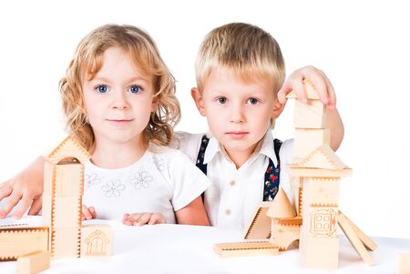 Two kids playing with wooden blocks indoor on white backgroundの写真素材