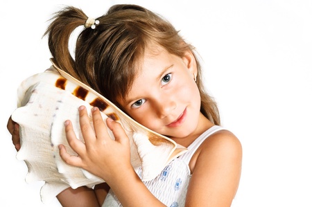 cute little girle listening a huge seashell isolated on whiteの写真素材