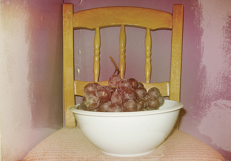 Vintage carved chair with a bowl of red grapes in retro styleの写真素材