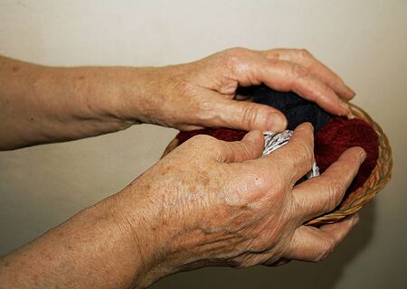 Hands of an old lady holding a basket with skeins knittingの写真素材