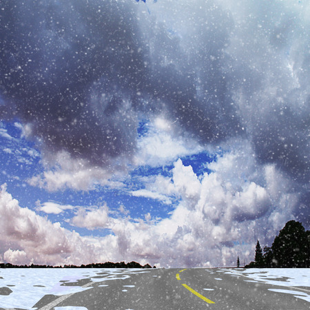 Winter panoramic landscape with road, silhouettes of trees, flying snow and clouds. White, gray and blue dramatic sky and highway with snow driftsの写真素材