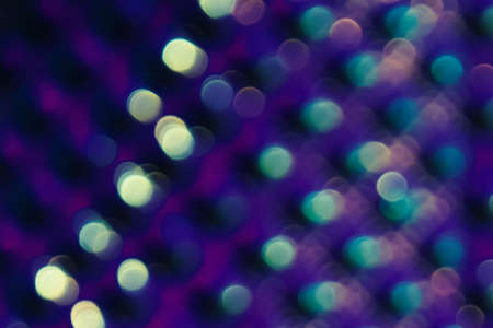 Garland in defocus on a ultraviolet background. bokeh effect with luminous particles. Light effect wallpaper. Bright abstract sparkling lines on a black background.の写真素材