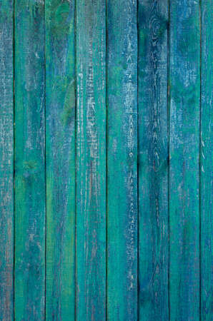 Backgrounds and texture concept. Pastel old vertical wooden fence painted in dark green and blue rugged paint in grunge styleの写真素材