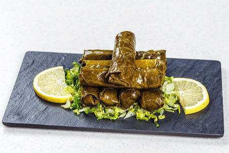 Dolma, stuffed grape leaves with rice and meat on black deck.