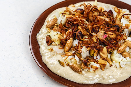 Hummus with olive oil and nuts on the brown plate