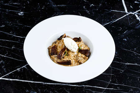 risotto with truffles served in the white plate on the black backgroundの写真素材