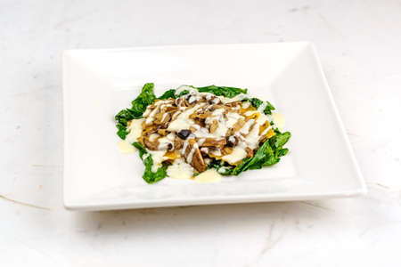 Italian ravioli with fresh roasted mushrooms and creamy parmesan cheese sauce decorated with spinach on white plate.の写真素材