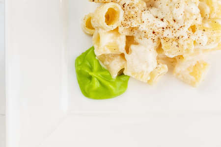 Penne pasta with a creamy sauce with parmesan cheese and spinach sause on a white plate on a marble surfaceの写真素材