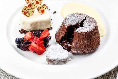 Chocolate fondant lava cake with ice cream strawberries and berries on white plate on marble serface