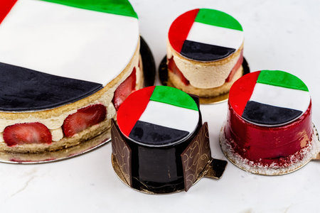 UAE National holiday celebration flag print cake and cupcakes on marble table