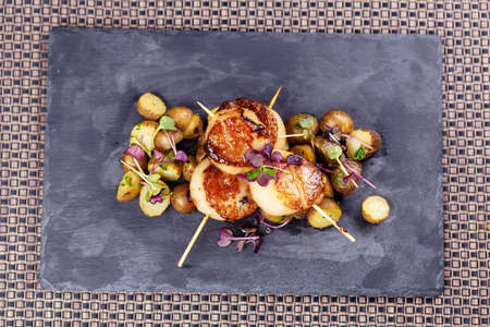 Grilled scallops with roasted young potatoes on stoneの写真素材