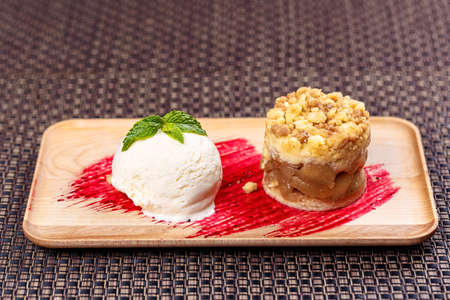 apple crumble with ice cream on wooden plateの写真素材